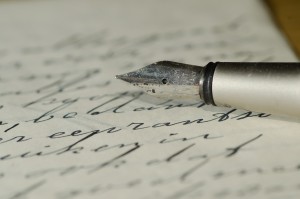 a dip pen on top of a paper with scribbled writing (zoom out)