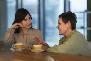 A cheerful young coach and an older student sit together, happily talking like close friends.